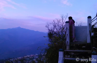 The sun has just set, a woman looks out over the valley from her home in Almora.