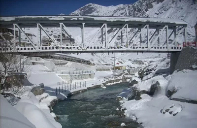 view of a snow covered bridge over Alaknanda river, flowing through Badrinath town.