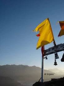 Gate of Chandrashila temple and view of sunrise rays on mountains in the backdrop.