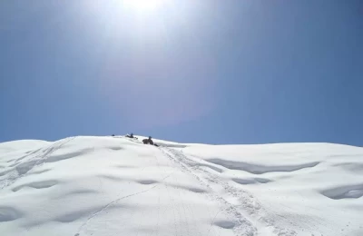 Trek route to Chandrashila during winter. A group of trekkers is enjoying skiing on snowy Mountain. 
