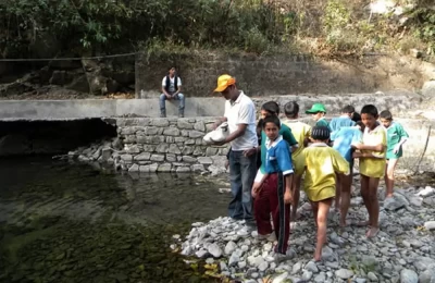 School Children feeding fish in nearby stream in Riya Village near Jeolikot