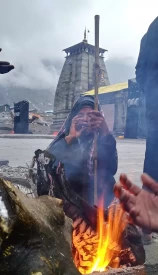 Kedarnath temple after a rainy day and travelers warming up themselves near to fire.