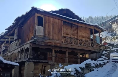 An old wooden house of Sankri village and snowy streets.