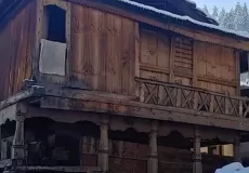An old wooden house of Sankri village and snowy streets.